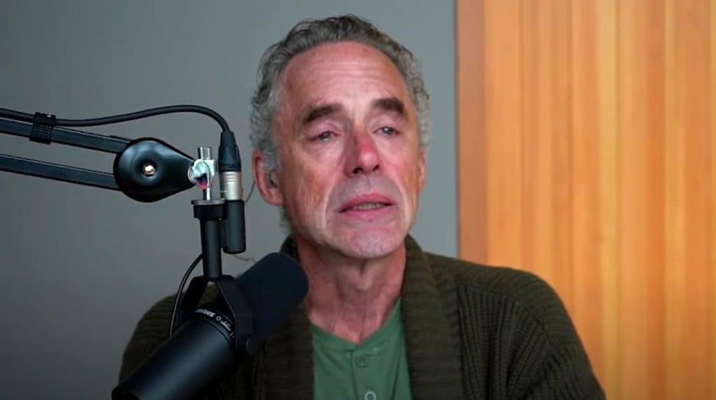 Jordan Peterson behind a microphone, crying